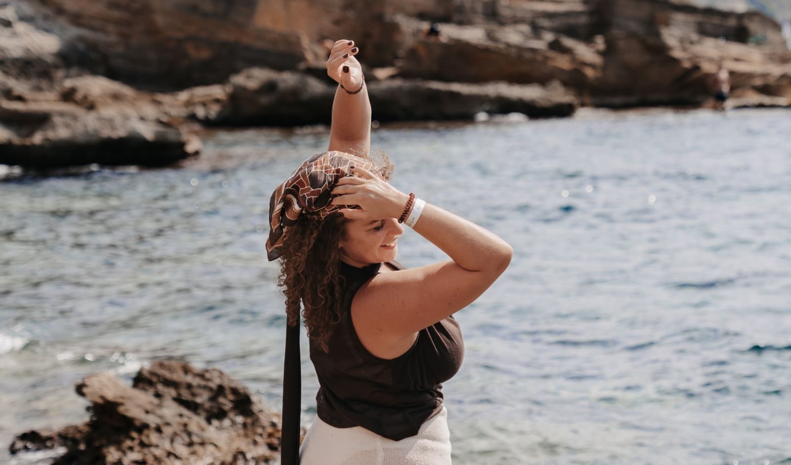 Franziska, voice coach for female entrepreneurs, by the sea in front of rocks